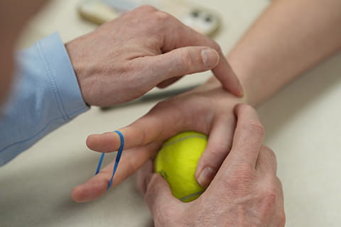 Two people working through some hand therapy actions.