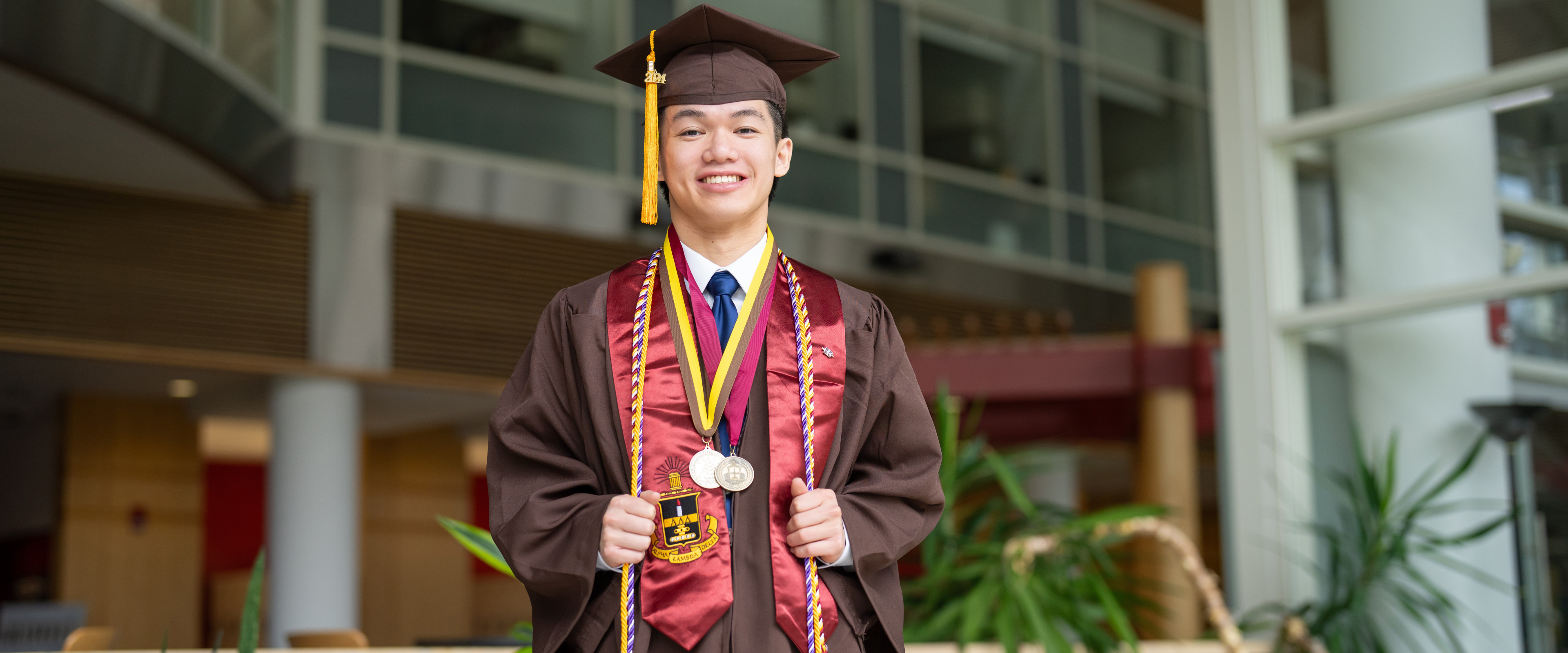 A portrait of David Le in his graduation cap and gown.