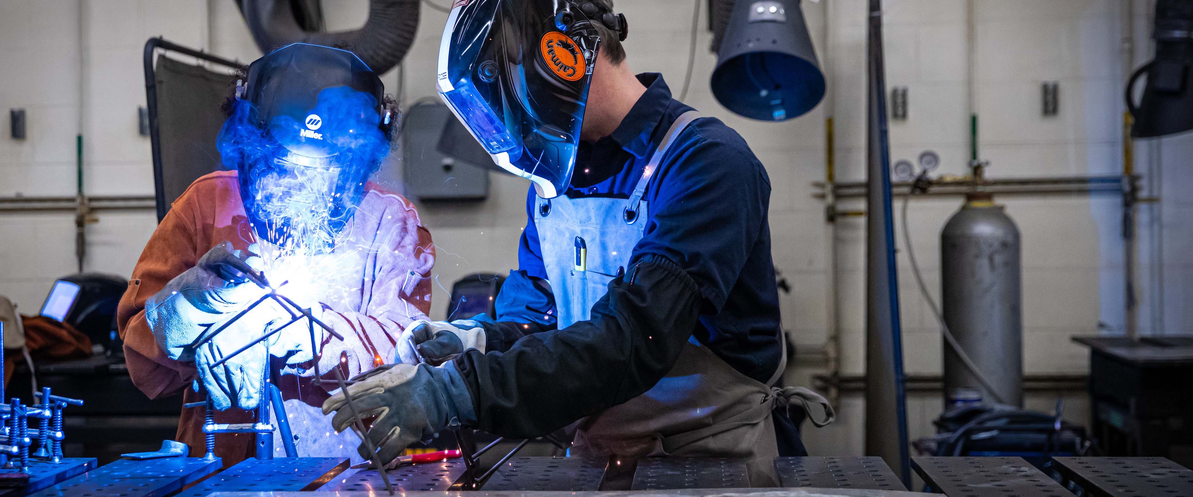 A student and teacher welding something in an art studio.