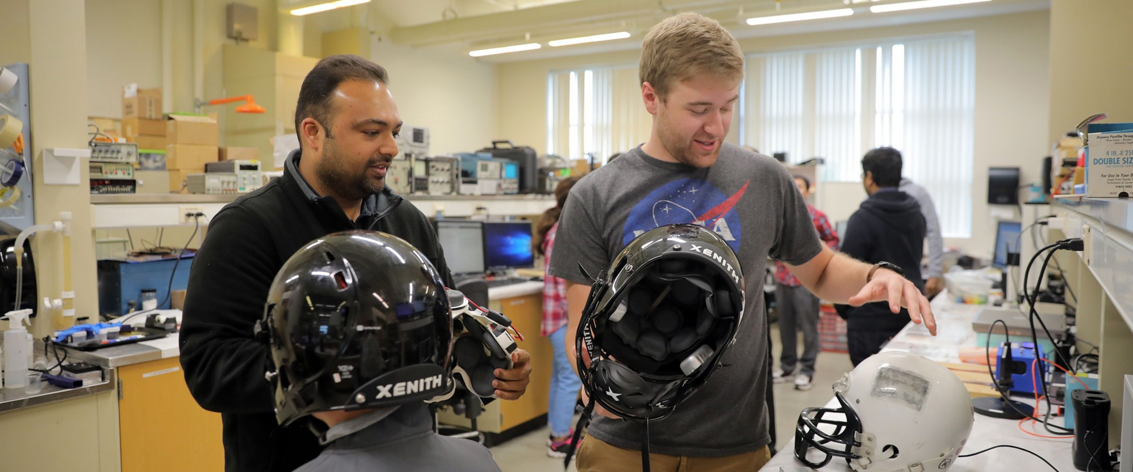 A WMU student and professor work together discussing the safety and design of the helmets they are holding
